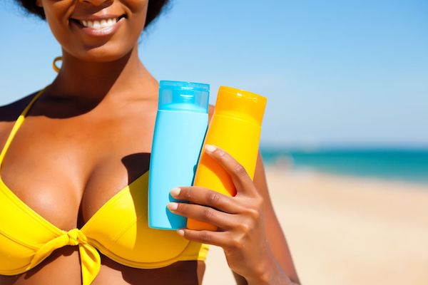 A woman on the beach holding sunscreen