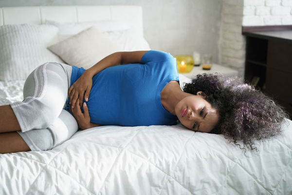 Crohn's disease A woman holding her stomach in pain on the bed