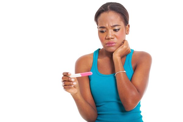 A worried woman looking at a pregnancy test