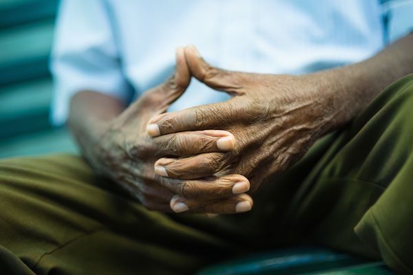 An elderly man holding his hands